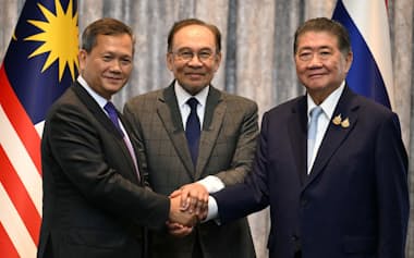握手するタイのプムタム首相代行㊨、カンボジアのフン・マネット首相㊧と、仲介したマレーシアのアンワル首相(28日、クアラルンプール近郊)=ロイター