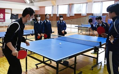外部指導者(左手前)とラリーする卓球部員(2023年、茨城県つくば市の市立谷田部東中学校)=一部画像処理しています
