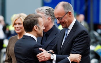 3日、記念式典でマクロン仏大統領㊧に駆け寄るメルツ独首相(西部ザールブリュッケン)=ロイター