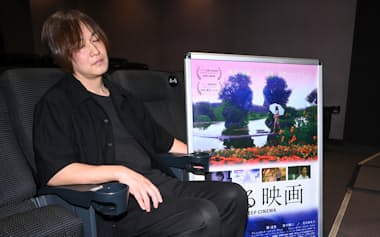 「寝る映画」の舞台挨拶で記念撮影に応じる曽根剛監督(東京都千代田区のヒューマントラストシネマ有楽町)