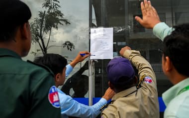 詐欺拠点となった建物に命令文を張り出すカンボジア当局者ら(16日、カンボジア南部タケオ州)=ロイター