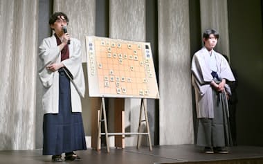 終局後、大盤解説会場であいさつする伊藤匠新王座。右は藤井聡太前王座(28日、甲府市)