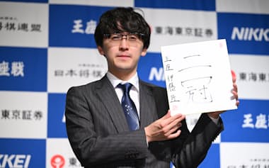 王座戦第5局から一夜明け、揮毫(きごう)した色紙を手に記念撮影に応じる伊藤匠新王座(29日午前、甲府市)