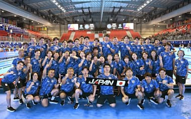 世界選手権の最終日、競技後に記念撮影する競泳日本代表の選手ら。前列でタオルを広げているのが倉澤委員長=共同