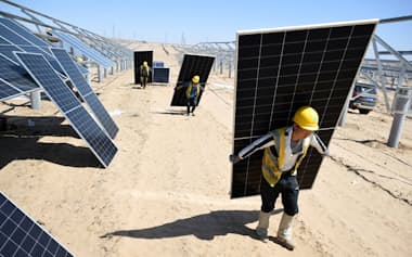 過剰生産解消への期待が高まっている(太陽光発電所でパネルの設置作業にあたる労働者ら)=ロイター
