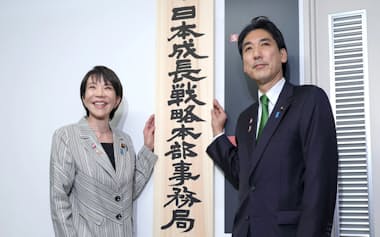 「日本成長戦略本部事務局」の看板を手に撮影に応じる城内実成長戦略相(右)と高市早苗首相(4日午前、東京都千代田区)=代表撮影