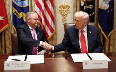 トランプ氏㊨とアルバニージー氏はレアアースを中心とした重要鉱物開発で合意文書に署名した=ロイター