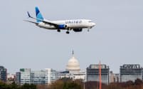 米議会議事堂の上空を飛ぶ航空機。主要空港は政府閉鎖で減便が相次いでいる(7日、米首都ワシントン)=ロイター