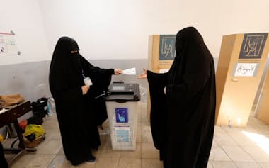 イラク中部ナジャフで9日、総選挙の事前投票をするイラクの女性有権者=ロイター