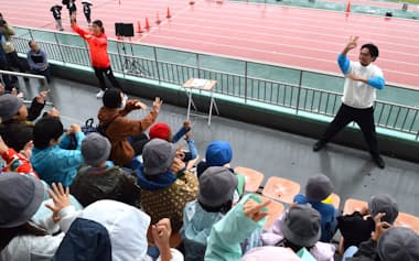 小学生に向けてサインエールを披露するデフアスリートの岡田海緒選手ら(10月、東京都品川区)