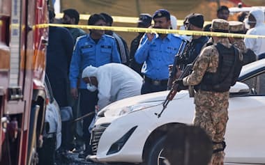 自爆テロの現場を調べるパキスタンの捜査官ら(11日、イスラマバード)=AP