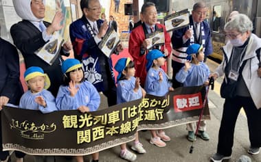 観光列車「はなあかり」でJR関駅を訪れた乗客を出迎える園児ら(12日、三重県亀山市)