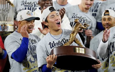 笑顔でワールドシリーズMVPトロフィーを掲げる山本(中央)=AP