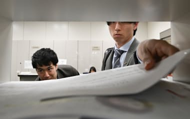 決算発表の集中日を迎え、資料を報道各社の棚に入れる企業の担当者(14日、東証)