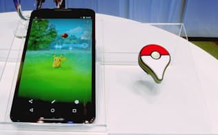 「ポケモン GO」を動作させたイメージを表示したスマホ（左）と「Pokemon GO Plus」（ピン留めタイプ）。2015年開催の発表会で撮影