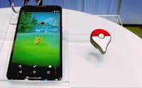 「ポケモン GO」を動作させたイメージを表示したスマホ（左）と「Pokemon GO Plus」（ピン留めタイプ）。2015年開催の発表会で撮影
