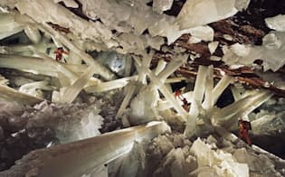 特殊な防護服を着て、ナイカ鉱山にある結晶洞窟内で巨大なセレナイトと呼ばれる透明な石膏の柱を調査する研究員たち。（PHOTOGRAPH BY CARSTEN PETER, NATIONAL GEOGRAPHIC CREATIVE）