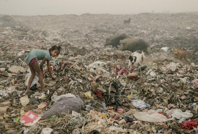 プラスチックを探す少女。ブホールスワのごみ捨て場は1日中燃え続けており、有害な煙の発生源になっているが、ごみを探しに多くの人びとがやって来る。（PHOTOGRAPH BY MATTHIEU PALEY, NATIONAL GEOGRAPHIC）