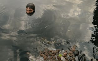 ごみが浮かぶ川から顔を出す少年。デリーでは河川の汚染が深刻な状況にある。（PHOTOGRAPH BY MATTHIEU PALEY, NATIONAL GEOGRAPHIC）