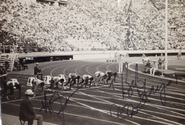 東京五輪100m走のスタートの様子。金メダルをとったボブ・ヘイズ氏（右下）、銀メダルのヒュゲロラ氏（左下）、スターターの佐々木氏（右上）のサインが入っている。紙焼きを筆者が撮影。写真提供は野崎忠信明星大学名誉教授、野崎忠信「1964年東京オリンピック大会コレクションと資料」所収