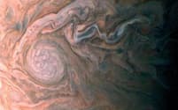 木星の南半球で渦を巻く楕円形の雲から細長い雲の流れが伸びている。2017年2月2日に嵐の上空約1500kmから撮影。アマチュア科学者のロマン・トカチェンコ氏が、色を再現してトリミングした。（PHOTOGRAPH BY NASA/JPL-CALTECH/SWRI/MSSS/ROMAN TKACHENKO）