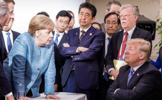 対峙するメルケル独首相とトランプ米大統領。その奥で腕組みする安倍首相=ロイター 対峙するメルケル独首相とトランプ米大統領。その奥で腕組みする安倍首相=ロイター