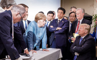 対峙するメルケル独首相とトランプ米大統領。その奥で腕組みする安倍首相=ロイター 対峙するメルケル独首相とトランプ米大統領。その奥で腕組みする安倍首相=ロイター