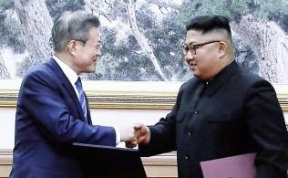 合意文書に署名し、握手する文在寅大統領(左)と金正恩委員長(19日)=聯合・共同 合意文書に署名し、握手する文在寅大統領(左)と金正恩委員長(19日)=聯合・共同