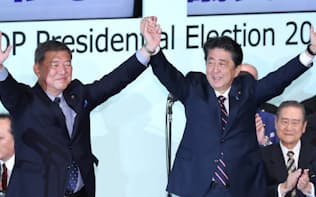 自民党総裁に選出され、石破元幹事長と手を取り合う安倍首相（20日午後、党本部）