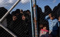 バグズからシリア北部のアルホル難民キャンプへ移送されてきた人々を、フェンスの向こうから眺める女性と子どもたち。彼女らはIS戦闘員の家族で、いまだにISを熱狂的に支持している（PHOTOGRAPH LYNSEY ADDARIO, NATIONAL GEOGRAPHIC）