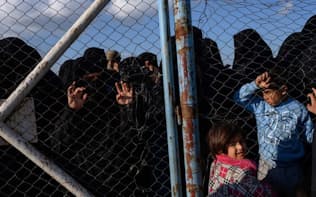 バグズからシリア北部のアルホル難民キャンプへ移送されてきた人々を、フェンスの向こうから眺める女性と子どもたち。彼女らはIS戦闘員の家族で、いまだにISを熱狂的に支持している（PHOTOGRAPH LYNSEY ADDARIO, NATIONAL GEOGRAPHIC）
