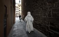 フィレンツェの狭い裏通りを歩くバルテー・コンティさん。1990年からレオナルド・ダ・ヴィンチの再現役者をやっている。言葉を発することなく匿名で演じられる再現役者が、自分には合っていると語る（PHOTOGRAPH BY PAOLO WOODS AND GABRIELE GALIMBERTI）