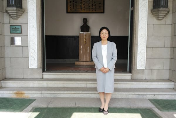 広島大学付属中学・高校の鈴木由美子校長。後ろは原爆の被害を受けながら倒壊を免れた講堂 広島大学付属中学・高校の鈴木由美子校長。後ろは原爆の被害を受けながら倒壊を免れた講堂