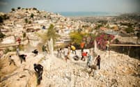 マグニチュード7.0の地震がハイチの首都を襲った2010年1月12日の翌日、少女の手当をする救急隊員。瓦礫は撤去されたものの、ハイチの経済状況は依然として厳しく、国民の3人にひとりが緊急の食糧援助を必要としている（PHOTOGRAPH BY EDUARDO MUNOZ, REUTERS）