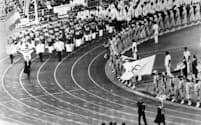 1980年モスクワ五輪の開会式で、英国チームの代表として五輪の旗を持つ英国オリンピック委員会事務総長のディック・パルマー氏（右手前の男性）。ソビエト連邦がアフガニスタンに侵攻したことを受け、英国の選手は開会式をボイコットした（PHOTOGRAPH FROM AP）