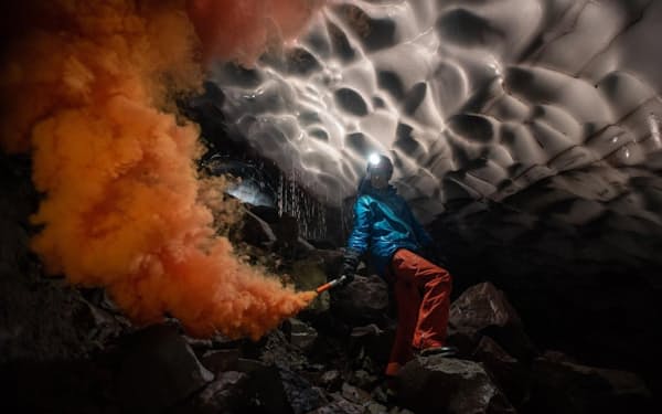 セントへレンズ山の火口に形成されたモスラ洞窟内で、発煙筒を点火するドイツ、ルール大学の科学者アンドレアス・フリッチ氏。その煙で、噴気孔から出る高温ガスがどのように洞窟を削り取ったかを調べることができる（PHOTOGRAPH BY ERIC GUTH）