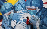 マレーシア、シャーアラムにある病院の外で、新型コロナウイルス検査のために綿棒でサンプルを採取する医師（PHOTOGRAPH BY LIM HUEY TENG, REUTERS）
