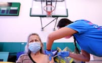 米カリフォルニア州のプロビデンス・ウィルミントン健康活動センターで、正看護師のダリル・ハナさんがコンセプシオン・ウィトロンさんに米ファイザー製の新型コロナウイルスワクチンを打っている。すでに発症したことがある人でも、ファイザー製などのmRNAワクチンを1回接種するだけで、この致命的な病気に対する免疫を高めることができる（PHOTOGRAPH BY MARIO TAMA, GETTY）