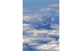 雲の上に立ち上る、噴火直後の御嶽山からのものみられる噴煙（27日午後0時1分、民間航空機から撮影）