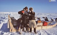 ナショナル ジオグラフィック協会の旗を手に、北極点で記念撮影をする植村とブロック