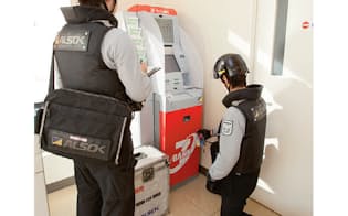 セブンイレブンに設置されたセブン銀行のATMに現金を補充・回収するALSOKの警備輸送担当者（写真:北山宏一）