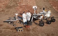 NASAの2人の技術者が、米国カリフォルニア州パサデナのジェット推進研究所（JPL）で開発された3世代の火星探査車と記念撮影。火星探査車キュリオシティは「車輪のついた実験室として構想されました」とバサバダ氏。（PHOTOGRAPH BY NASA/JPL-CALTECH ）