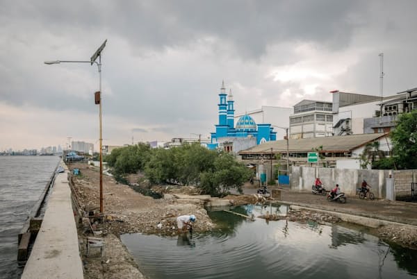 商店、住宅、モスクを浸水から守るジャカルタ湾の防波堤。海面上昇と地下水の過剰揚水を理由に、インドネシアの首都ジャカルタは世界で最も早く沈む都市の一つと考えられている(PHOTOGRAPH BY IAN TEH, PANOS PICTURES/REDUX) 商店、住宅、モスクを浸水から守るジャカルタ湾の防波堤。海面上昇と地下水の過剰揚水を理由に、インドネシアの首都ジャカルタは世界で最も早く沈む都市の一つと考えられている(PHOTOGRAPH BY IAN TEH, PANOS PICTURES/REDUX)